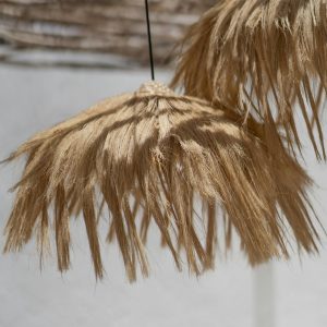 Artistic boho style natural reed lampshades hanging outdoors in soft ambient light.