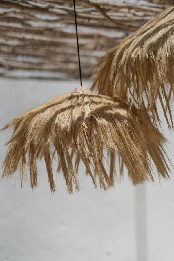 Artistic boho style natural reed lampshades hanging outdoors in soft ambient light.