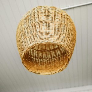 Close-up of a rustic wicker lampshade hanging from a ceiling, offering a warm vibe.