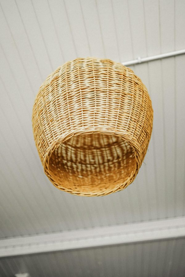 Close-up of a rustic wicker lampshade hanging from a ceiling, offering a warm vibe.