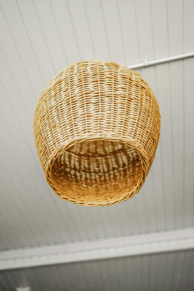 Close-up of a rustic wicker lampshade hanging from a ceiling, offering a warm vibe.