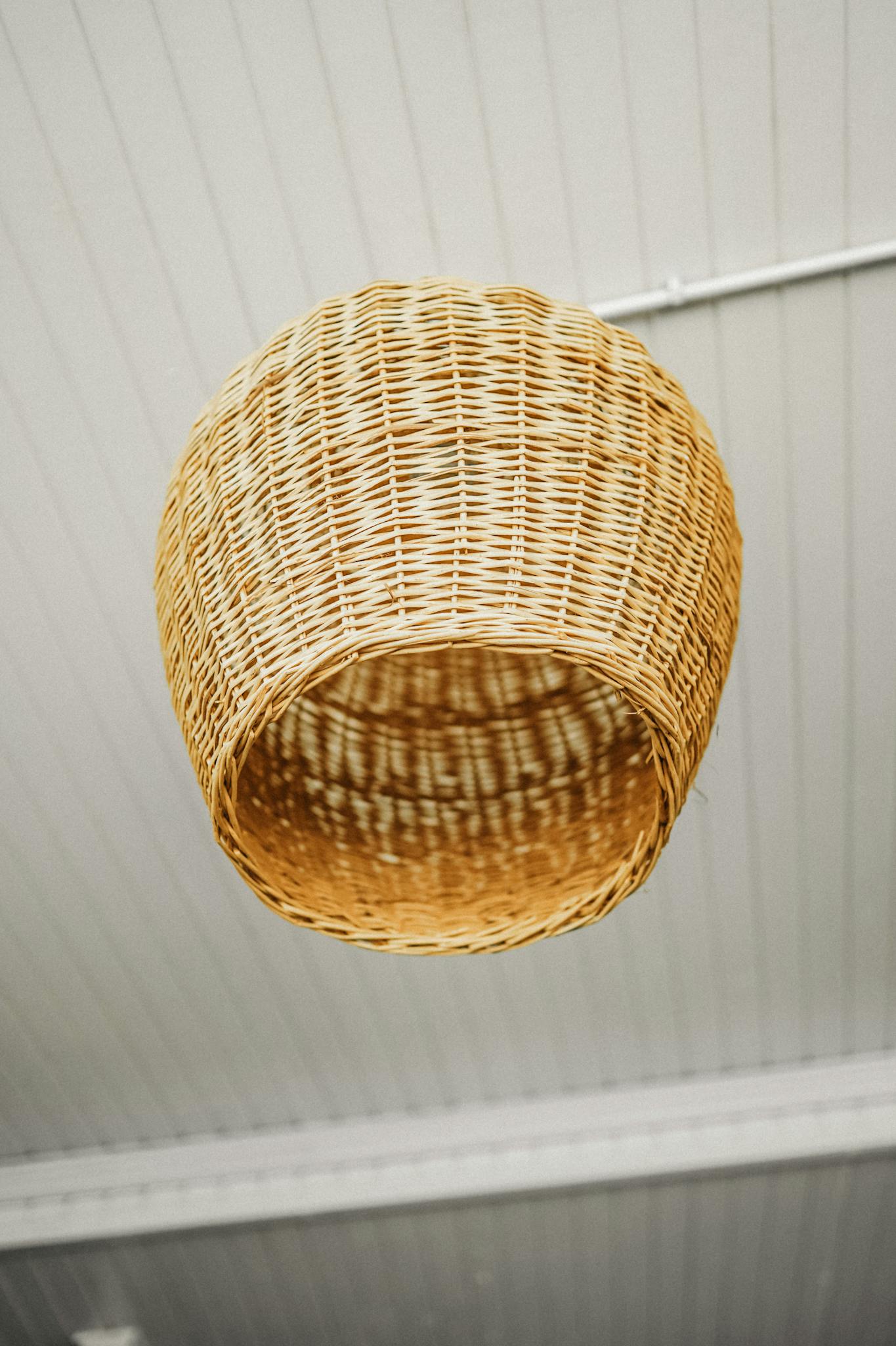 Close-up of a rustic wicker lampshade hanging from a ceiling, offering a warm vibe.